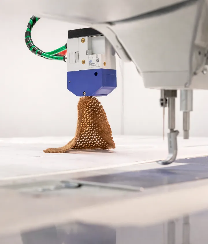 Close-up of ADOTC robotic textile handling with gripper and sewing environment